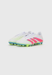 Witte voetbalschoenen met roze en paarse accenten, voorzien van een gestructureerde bovenkant, ronde neus en een meerkleurige gestifte zool.