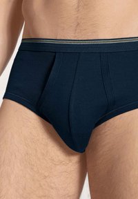 Navyblauwe katoenen slip met een strakke pasvorm, een elastische tailleband met contrasterende strepen en een gladde textuur.
