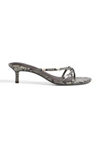 Sandal s črno-belo teksturo usnjenega vzorca z tankim trakom in 6,35-centimetrskim stiletto peto. Mehka teksturirana notranja podloga z minimalnimi detajli.