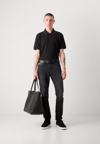 Schwarzes Polohemd mit einem Kontrastkragen, schwarze Jeans, schwarze Sneakers und eine schwarze Ledertasche. Schlichtes Design und elegante Materialien.
