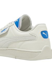 Biały skórzany sneaker z niebieskimi akcentami, teksturowaną boczną płytą i wyściełanym kołnierzem. Na pięcie znajduje się logo, a podeszwa jest kontrastująca.