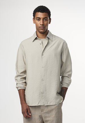 Ljust beige skjorta med knapp-up och en subtil strukturerad finish samt långa ärmar, med en klassisk krage och silverfärgade knappar.