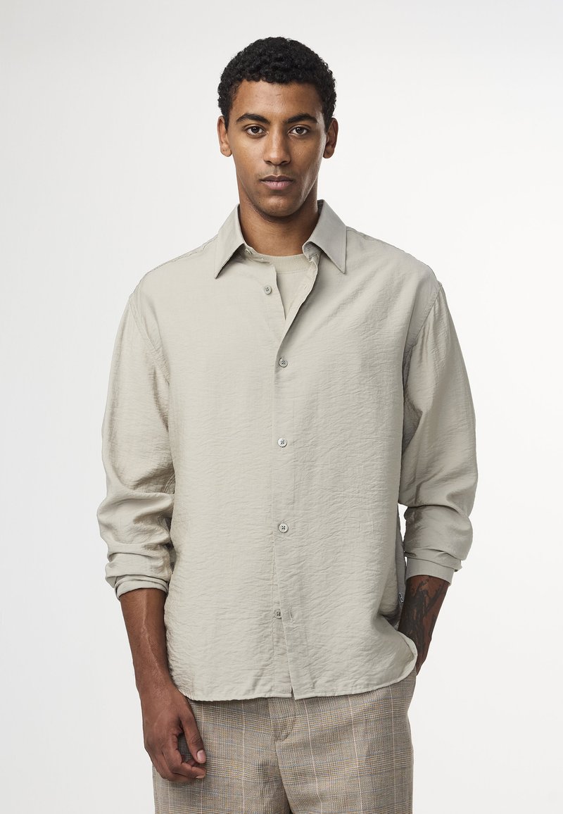 Ljust beige skjorta med knapp-up och en subtil strukturerad finish samt långa ärmar, med en klassisk krage och silverfärgade knappar.