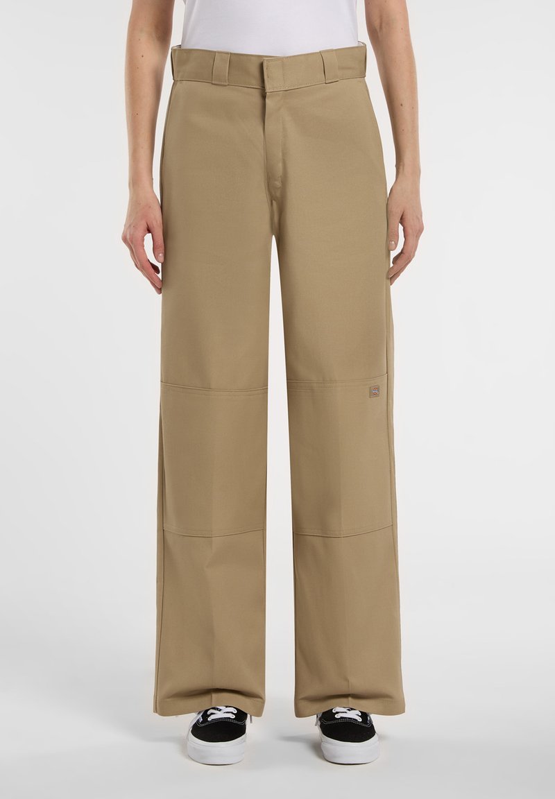 Khaki vida-byxorna med hög midja, tillverkade av slitstarkt tyg, med horisontella söms accentuerade och fickor. I kombination med svarta skor.