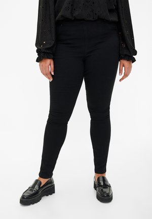 Black leggings in a stretchy fabric, fitted design, high-waisted, paired with chunky black loafers. Smooth texture, no patterns or accents.