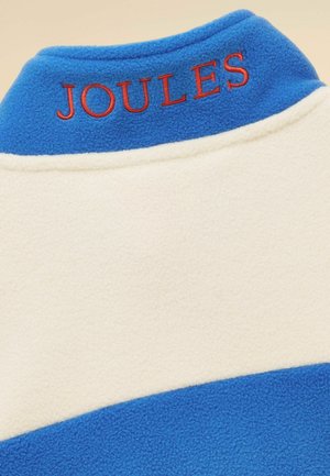 Col col en polaire bleu et crème avec le texte "JOULES" brodé en rouge à l'arrière.