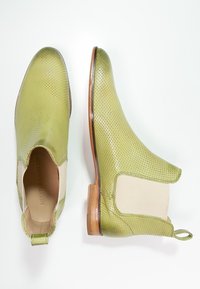 Botas de tobillo de cuero perforado verde con paneles laterales elásticos y un tacón de madera. Textura suave y diseño de punta redondeada.