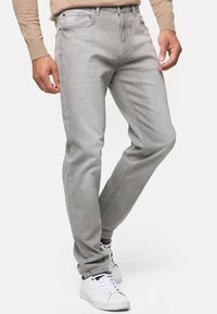 Pantalones vaqueros gris de corte recto, con un diseño clásico de cinco bolsillos y costuras sutiles, combinados con zapatillas blancas.