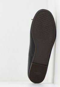 Czarna skórzana shoes z gładką cholewką i teksturowaną brązową gumową podeszwą. Posiada okrągły czubek i subtelne logo na podeszwie.