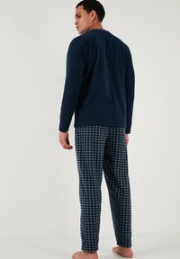 Námořnická dlouhá mikina v kombinaci s kostkovanými pyžamovými kalhotami, které mají měkkou texturu a volný střih; obojí navrženo pro maximální pohodlí.