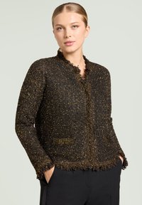 Black and gold textured jacket with a fringed collar and edges, featuring two pockets and a fitted design.