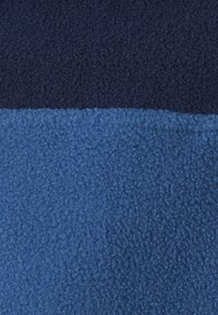 Tofarvet fleece-stof med en tekstureret, blød og luftig overflade i mørk marineblå og lysere blå vandrette bånd.