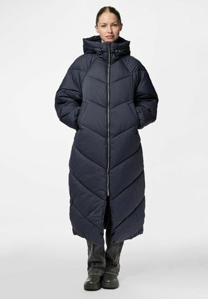 Manteau matelassé long, bleu marine, avec une capuche, présentant un motif en chevrons, une fermeture éclair frontale et des poches latérales. Le matériau semble lisse et isolé.