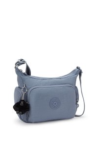 Borsa a tracolla blu Kipling con tasca frontale con zip, tracolla regolabile e un piccolo portachiavi a forma di scimmia nera attaccato alla zip laterale.