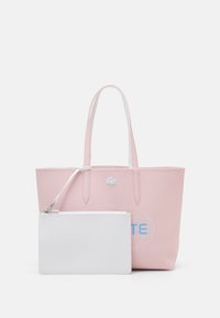 Sac fourre-tout rose avec doubles poignées et poche zippée blanche amovible, arborant un petit logo crocodile et un texte bleu à l'avant.