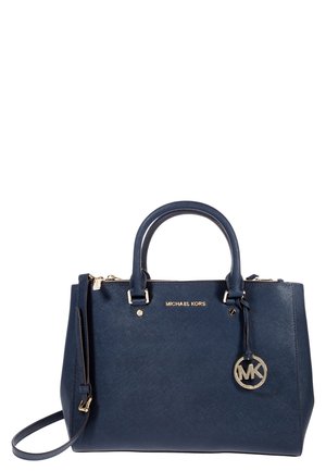 Sac à main Michael Kors bleu marine avec deux anses, une bandoulière, une plaque logo dorée et un charm rond MK suspendu sur le côté droit à l’avant.