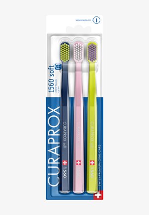 Drei Curaprox 1560 weiche Zahnbürsten in Blau, Pink und Gelb, in Originalverpackung mit Schweizer Flagge und Produktdetails.