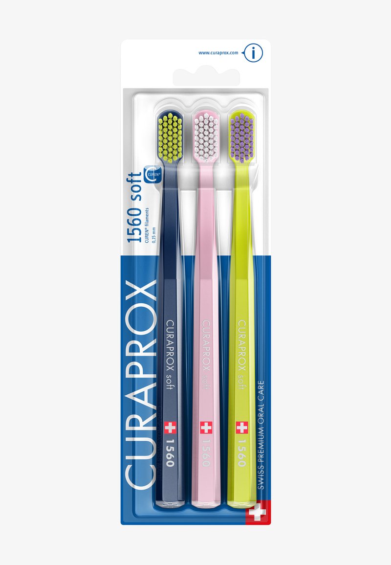 Drei Curaprox 1560 weiche Zahnbürsten in Blau, Pink und Gelb, in Originalverpackung mit Schweizer Flagge und Produktdetails.
