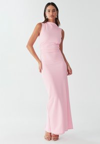 Prilegla roza večerna obleka z visokim izrezom in nabranim pasom, ki sega do tal in ima gladko teksturo tkanine.