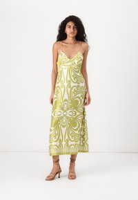 Vestido maxi com decote em V profundo, alças finas, padrão abstrato em verde e branco, e um corpete ajustado que se transforma numa saia ampla.
