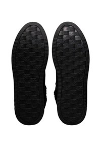 Zwarte rubberen schoenzolen met een geponst patroon, voorzien van een dambordontwerp en zijgroeven voor grip.