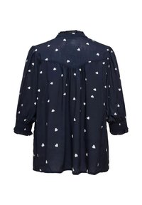 Mørkeblå bluse med hvidt hjerte mønster, lange ærmer med smockede manchetter, afslappet pasform og en samlet rygdetalje. Letvægtsstof.