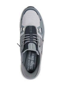 Zapatilla atlética gris con parte superior de malla, detalles texturizados, cordones elásticos y etiqueta "Skechers Slip-ins" en la plantilla.