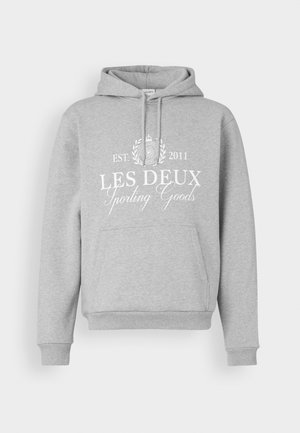 Grå hoodie i mjukt material med en framficka, dragsko huva och vit tryckt text: "LES DEUX Sporting Goods EST. 2011."