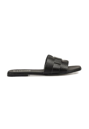 Sandalia deslizante de cuero negro que presenta una parte superior texturizada con diseño trenzado, suela plana y un tacón ligeramente elevado. Nombre de la marca "KAMOME" visible.