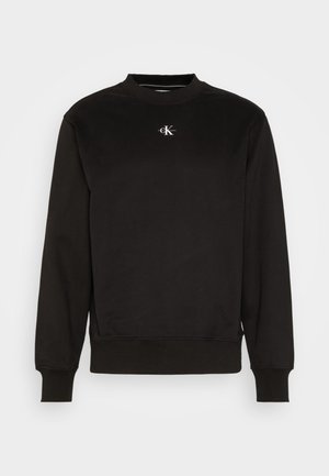 Černá mikina s kulatým výstřihem, žebrovanými manžetami a lemem, s malým bílým logem Calvin Klein uprostřed na hrudi.