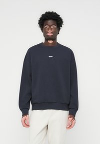 Sweatshirt de felpa azul marinho com gola redonda, ombros caídos, punhos e bainha canelados; possui o logótipo branco "BOSS" no peito.
