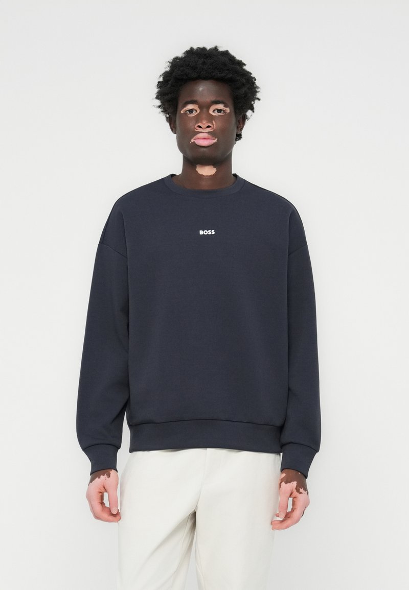 Sweatshirt de felpa azul marinho com gola redonda, ombros caídos, punhos e bainha canelados; possui o logótipo branco "BOSS" no peito.