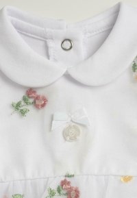 Robe blanche pour bébé avec col Peter Pan, broderie florale rose et verte, nœud blanc et pendentif rond avec une initiale "C".