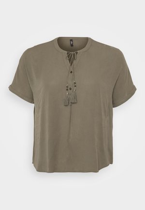 Khaki kortærmet bluse med rund halsudskæring, frontlukning med knapper og dekorative frynser med perler ved snøresdetaljen. Glat stoftekstur.