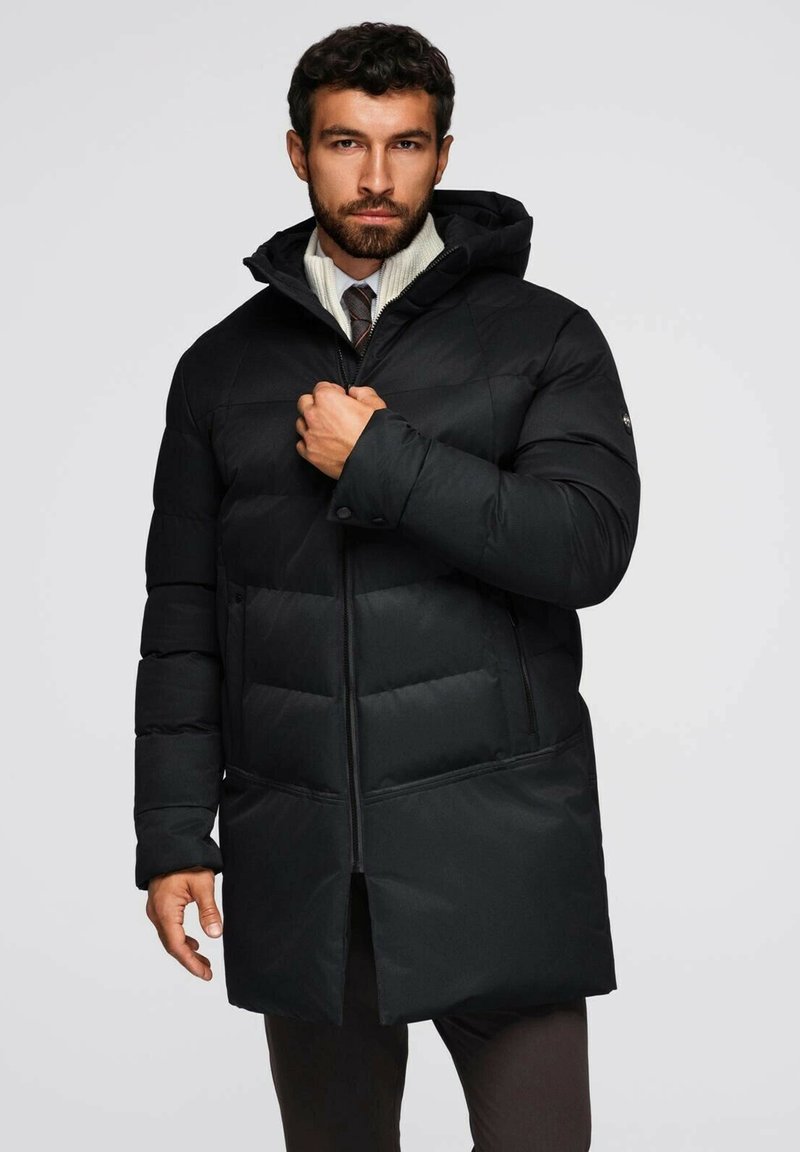 Giacca a vento nera imbottita con cappuccio, dotata di chiusura con zip frontale, motivo trapuntato e due tasche laterali. Finitura liscia e opaca con una vestibilità sartoriale.