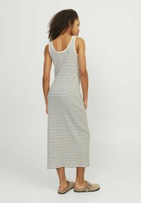 Abito a righe, senza maniche, con una silhouette aderente. Realizzato in tessuto morbido a righe creme e blu navy, presenta una scollatura a barco e una lunghezza midi.