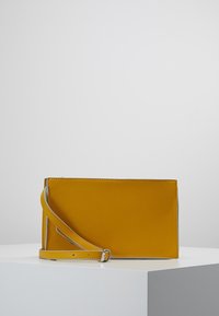 Clutch in similpelle gialla con texture liscia, forma rettangolare e tracolla staccabile. Presenta bordi cuciti e un design minimalista.