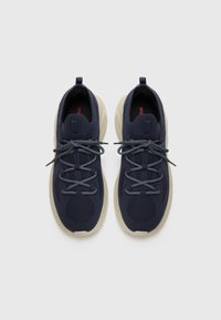 Mørkeblå joggesko med mesh-overdel, rund tå og beige gummisåle. Har grå snøring og et fremtredende rødt merke innvendig.