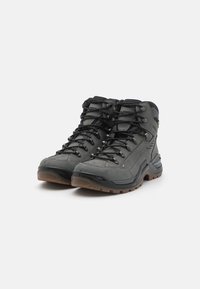 Graue Wanderschuhe mit hohem Knöcheldesign, strukturiertem synthetischem Obermaterial, schwarzen Schnürsenkeln und Gummisohle mit multidirektionalem Profil.