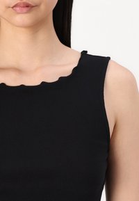 Top de tirantes negro con canalé, con un escote festoneado y diseño sin mangas, que muestra una textura suave y una forma ajustada.