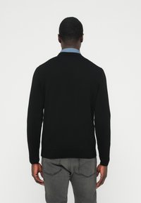 Pulover negru cu gât rotund, mâneci lungi și tiv striat. Confecționat dintr-un material tricotat fin, are un design simplu, fără ornamente.