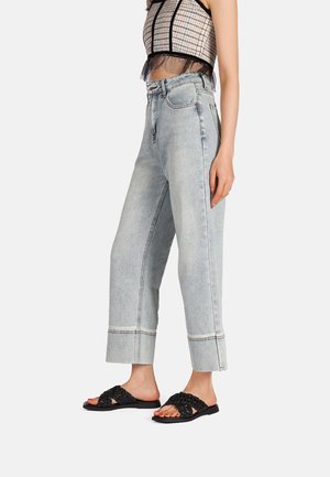 Jeans in denim azzurro chiaro a vita alta con gambe ampie e orli arrotolati. Abbinate a sandali neri intrecciati slip-on.