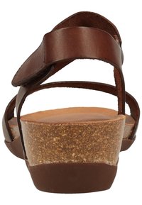 Sandali in pelle marrone con zeppa in sughero, apertura sul retro e dettaglio della cinghia regolabile. La texture include pelle liscia e sughero granato.