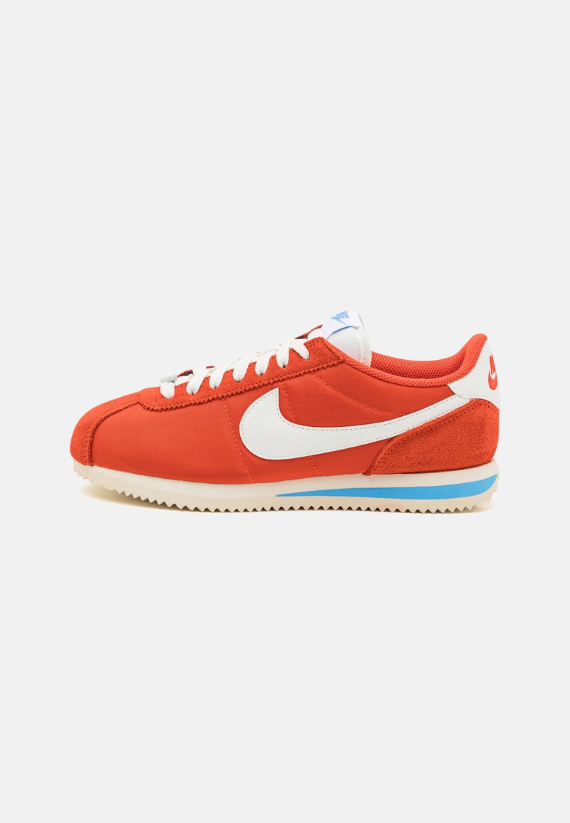 Red canvas and suede sneaker with white Swoosh logo, blue accent stripe, and textured outsole. Features white laces and a padded collar.