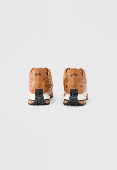 Καφέ δερμάτινα αθλητικά παπούτσια με μαύρες λεπτομέρειες και διακοσμητικό σχέδιο. Διαθέτουν λογότυπο MCM στη φτέρνα και υφή σε μαύρη εξωτερική σόλα.
