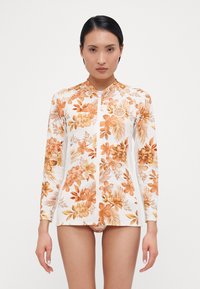 Long-sleeve rash guard in white with orange floral pattern. Features a zip front, collar, and lightweight, stretchy fabric.
