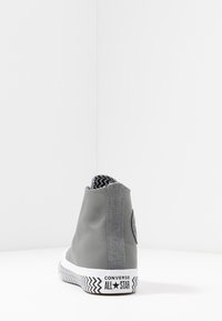 Baskets montantes grises avec dessus en cuir, accents en daim et doublure intérieure à motifs. Semelle en caoutchouc avec un motif en zigzag.