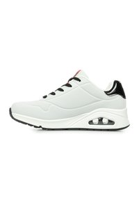 Sneaker atletico bianco con lacci neri, dettagli neri lucidi nel tallone e suola in gomma testurizzata con una tasca d'aria visibile.