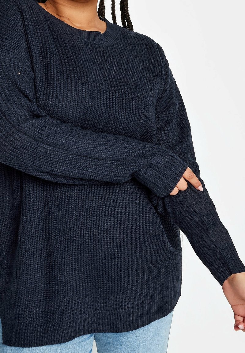 Dunkelblauer gestrickter Pullover mit strukturiertem Oberflächen, Rundhalsausschnitt und langen Ärmeln. Die Ärmel verfügen über Daumenlöcher für zusätzlichen Komfort.