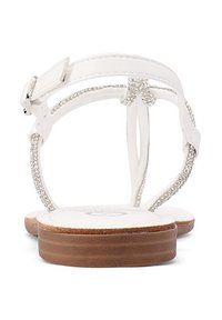 Sandali piatti bianchi con tomaia in pelle liscia, cinture sottili e una fila decorativa di strass lungo il centro. Suola in legno marrone.